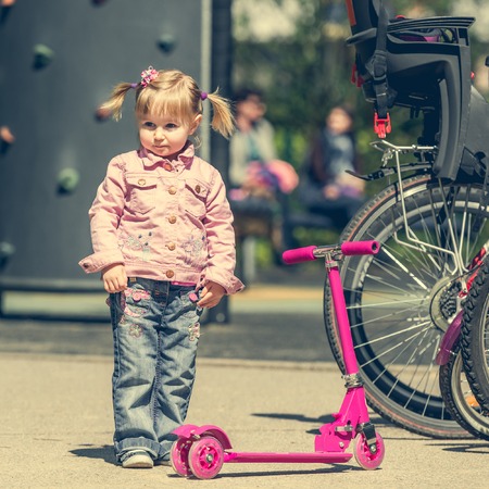 little girl with her scooter on a bicycle parkingの写真素材