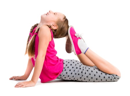 little girl doing an exercise on the floor isolated on white backgroundの写真素材