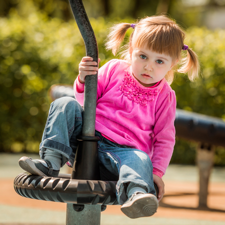Cute little girl on outdoor playground equipmentの写真素材