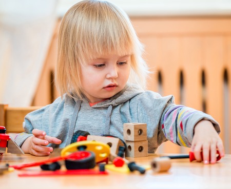 cute two-year old baby girl at home in the nursery playing with constructorの写真素材