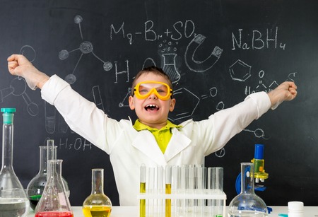 excited schoolboy with hands up in chemistry lab made a discoveryの写真素材