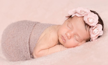 newborn cute girl sleeping on a pink backgroundの写真素材