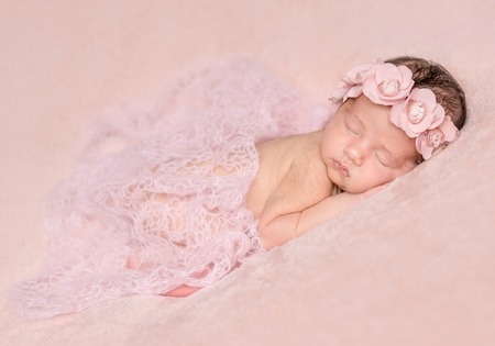 newborn cute girl sleeping on a pink backgroundの写真素材