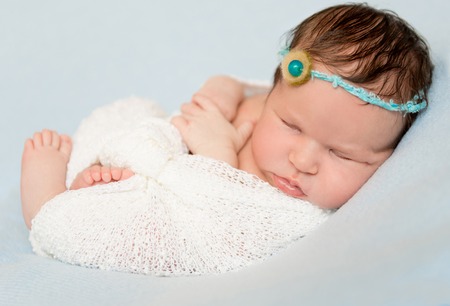 lovely sleeping wrapped baby with bare crossed feet and handsの写真素材