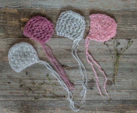 set of tender knitted pink and white hats for newborn on wooden backgroundの写真素材