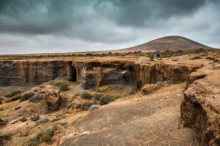 Lanzarote terrain with rocks and cliffs with gray cloudy sky on the background, Spainの写真素材