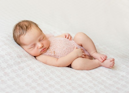lovely newborn girl sleeping on pink blanket with bare feetの写真素材