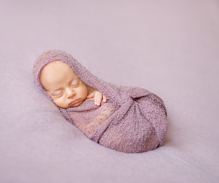 lovely sleeping newborn baby swaddled in pink diaperの写真素材