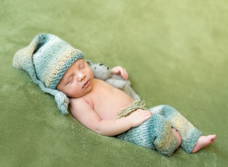 lovely newborn baby in knitted hat and panties sleeps curled up, top viewの写真素材