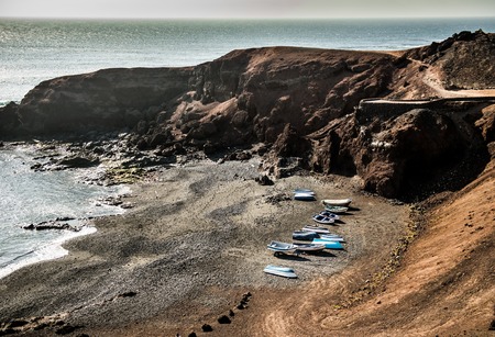 rocky shore with fishing boats in Canary Island bay, Lanzarote, Spainの写真素材