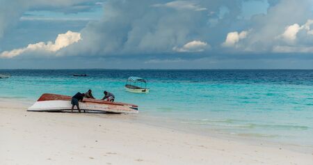 ZANZIBAR, TANZANIYA- JULY 16: african fishermen repairing boat on Zanzibar beach on July 16, 2016 in Zanzibar, Tanzaniaのeditorial素材