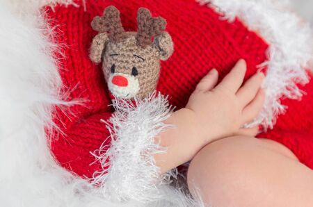 cute sleeping newborn baby in red hat on little bed with fluffy blanketの写真素材
