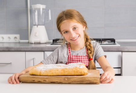 beautiful litte girl with baked apple strudel on tableの写真素材
