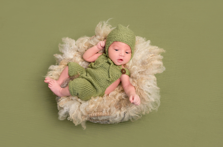 Baby in knitted costume, funny poseの写真素材