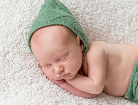 cute newborn sleeping in green elf hat and pantiesの写真素材