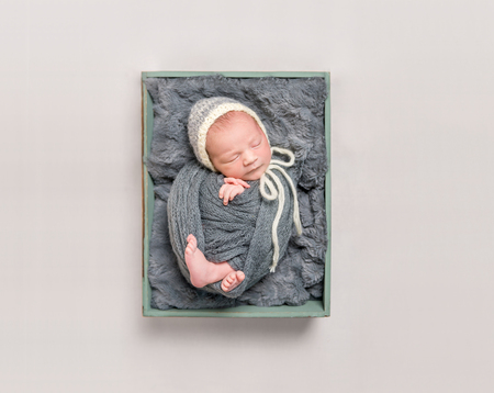 Baby wrapped in gray blanket resting, topshotの写真素材