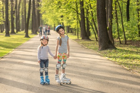 Sisters roller blading together, holding handsの写真素材