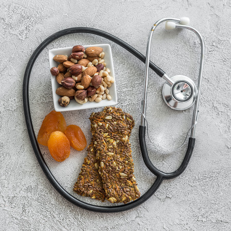 Stethoscope and heart with dried fruits and nuts on a gray backgroundの写真素材
