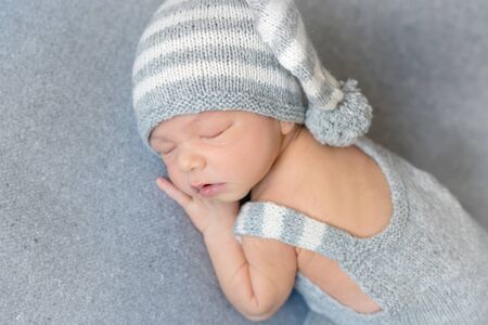 sleeping newborn boy in a hatの写真素材