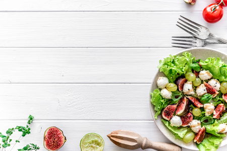 Salad with figs, mozzarella and grapes on a white wooden background.の写真素材