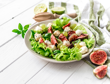 Salad with figs, mozzarella and grapes on a white wooden background.の写真素材