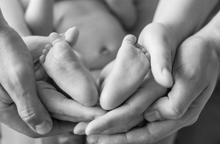 Baby feet in the hands of mom and dadの写真素材