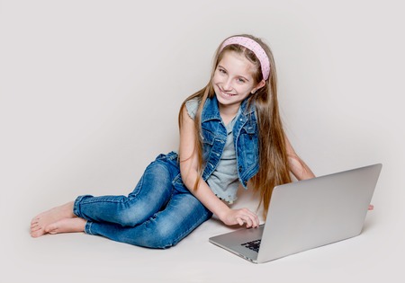 Litlle girl lying on floor with laptop