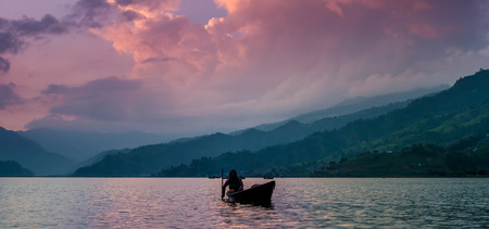 fisherman in a boat on the lake in Pokhara at sunsetの写真素材