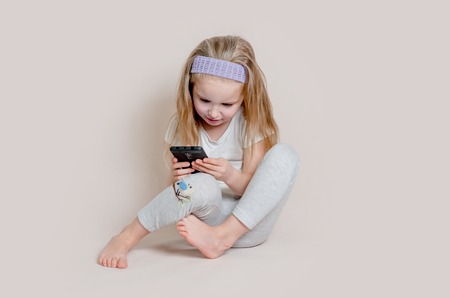 Blonde little girl playing with smartphoneの写真素材