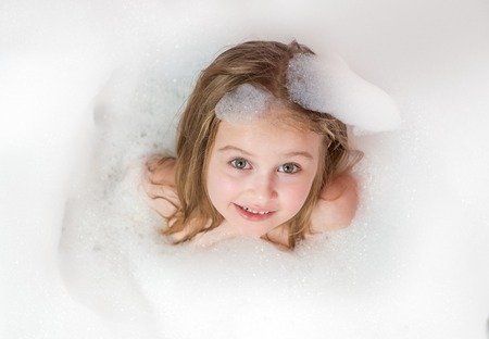 Little girl bathes in a bath with foam and bubbles