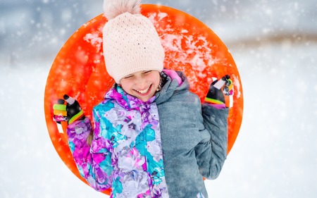 Funny girl with saucer sled outdoorsの写真素材