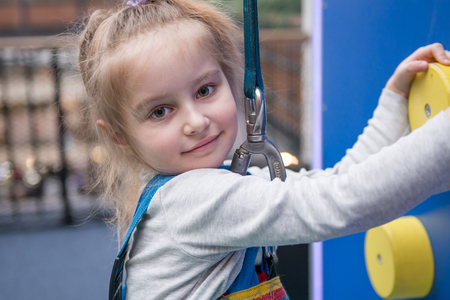 Close-up portrait of teen girl on the climbing wall in entertainment centerの写真素材