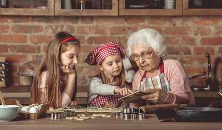 Grandma and granddaughters spreading doughの写真素材