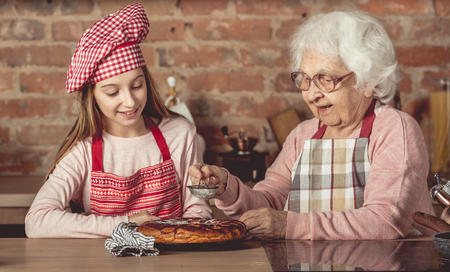 Granny with her granddaughter cooking pieの写真素材