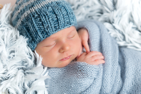 Newborn infant sleeping in box among blue blanketsの写真素材