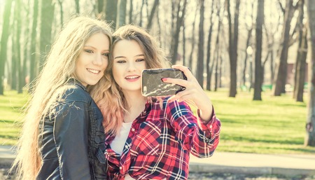 Happy girl friends taking a selfie on a summer dayの写真素材