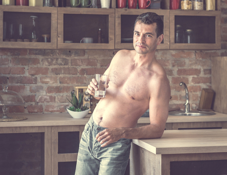 athletic man drinks water with lemon in the kitchenの写真素材