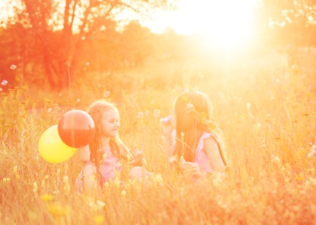Two little sisters blowing soap bubblesの写真素材