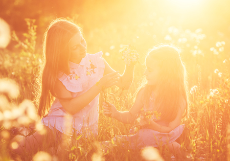 Two little sisters weave wreaths of flowersの写真素材