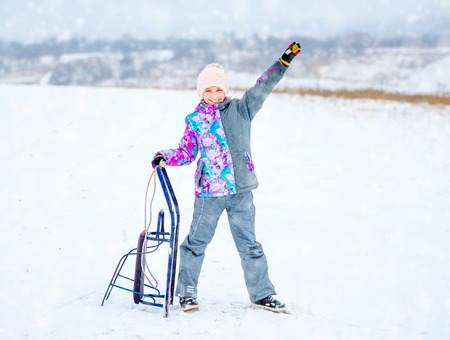 Girl in ski costume holding sledges