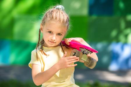 Cute little girl with a skateboard on her shoulderの写真素材
