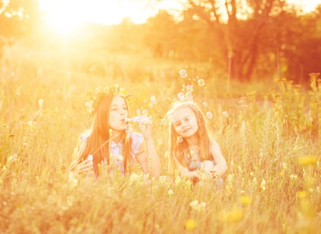 Two little sisters blowing soap bubblesの写真素材