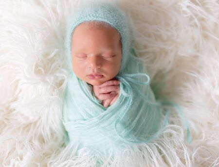 Newborn baby lying with knitted toy
