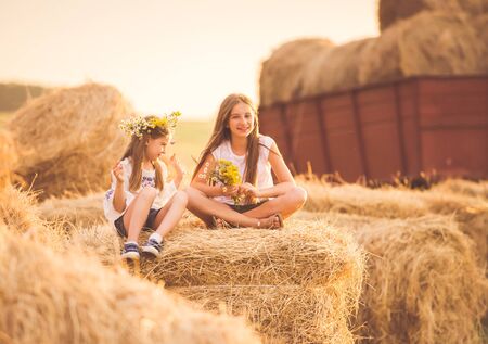 Small cute girls resting on the sunny fieldの写真素材