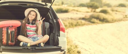 Little cute girl in the trunk of a car with suitcasesの写真素材