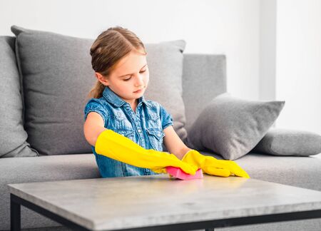 Little girl cleaning wooden tableの写真素材