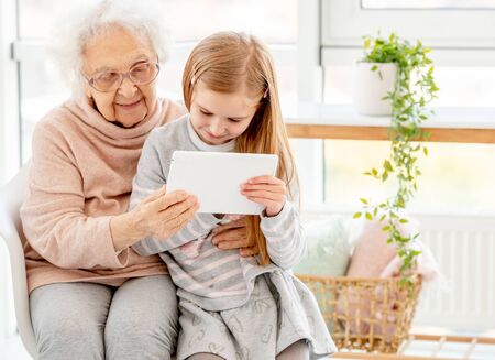 Granddaughter with granny using tabletの写真素材