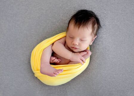 Lovely newborn in yellow blanketの写真素材