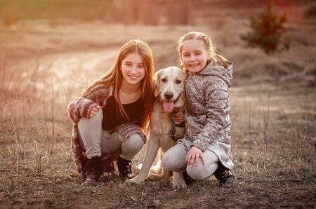 Cute sisters hugging dog outdoorsの写真素材