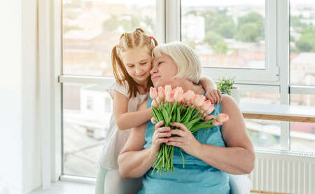 Pretty little girl kissing happy grandmother